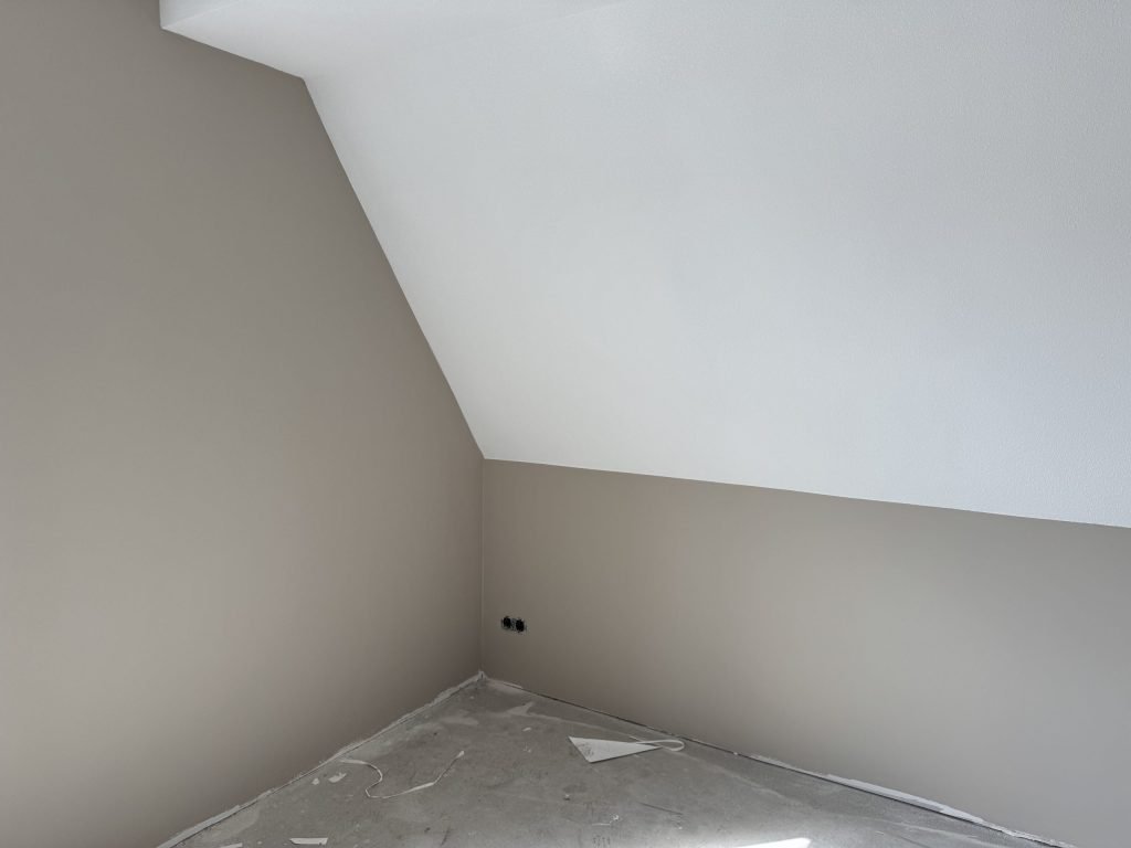 Slaapkamer met een schuine wand onder het dak, de rechte muren in beige vlies en het schuine deel wit