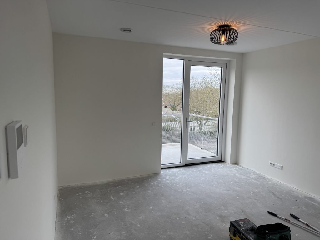 Nieuwe slaapkamer met openslaande balkondeuren en lichte wanden, kort na de oplevering